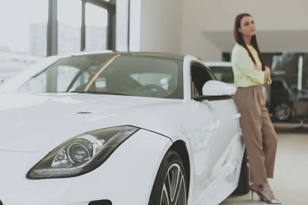 Elegante jonge vrouw die het kopen van nieuwe auto bij de dealer — Stockfoto