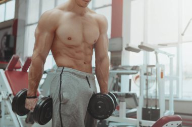 Gömleksiz adam salonunda dumbbells ile egzersiz sökük
