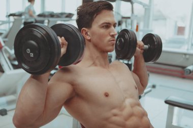 Gömleksiz adam salonunda dumbbells ile egzersiz sökük