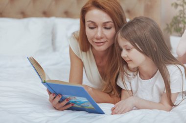 Sevimli kadın küçük kızına bir kitap okuma