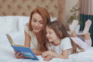 Sevimli kadın küçük kızına bir kitap okuma