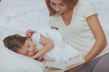 Sevimli kadın küçük kızına bir kitap okuma