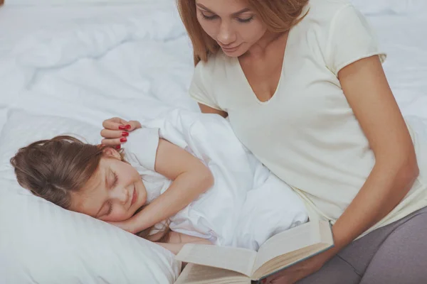 彼女の小さな娘に本を読んでいるチャーミングな女性 — ストック写真