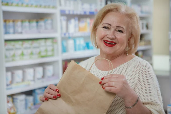 Güzel yaşlı kadın eczaneden alışveriş yapıyor.