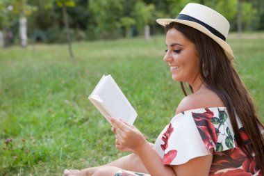 Şehvetli bir kadının profil fotoğrafı gülümseyen, parkta kitap okuyan.