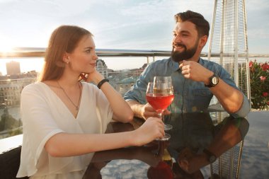 Güzel bir çiftin bar terasında romantik bir randevusu var, şarap içip sohbet ediyorlar.