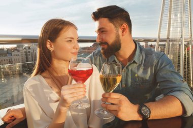 Hoş bir genç çift yıldönümünü kutluyor, gün batımında dışarıda şarap içiyor.