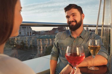 Restoranın terasında birlikte şarap içerken kız arkadaşına gülümseyen mutlu yakışıklı adam.