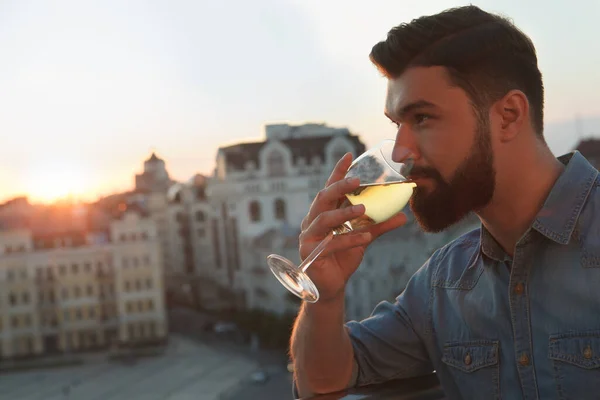 Close up of a bearded man sipping wine outdoors on sunset