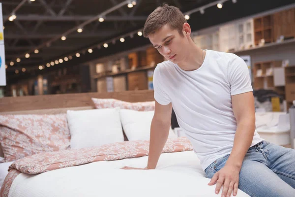 Молодой Человек Осматривает Новую Кровать Магазине Мебели — стоковое фото