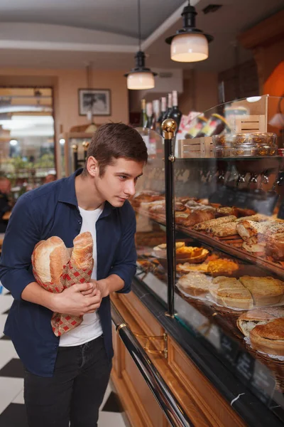 パン屋のディスプレイからデザートを選ぶ男性の顧客の垂直ショット — ストック写真