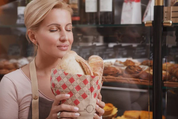 Красивая Зрелая Пекарь Нюхает Ароматный Свежий Хлеб Закрытыми Удовольствия Глазами — стоковое фото