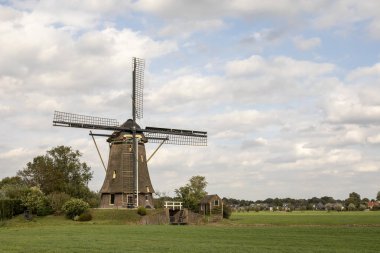 Mera mavi bir bulutlu gökyüzü altında çevrili Hollanda kırsal kesimde geleneksel Hollanda Yeldeğirmeni. 