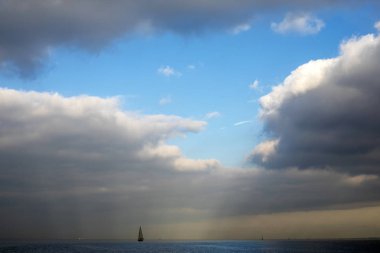 Gökyüzünün parlak mavi parçaları ile sakin bir göl üzerinde bir yelkenli yelkenli.