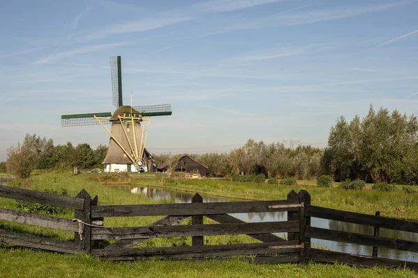Moinho de vento holandês tradicional com lagoa no campo . — Fotografia de Stock