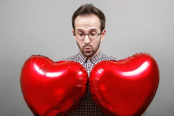 The guy on a gray background with an inflatable ball in the hands of a heart