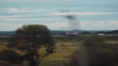 Karavanlı büyük kamyon ağaçlarla dolu dar bir yol boyunca ilerliyor.