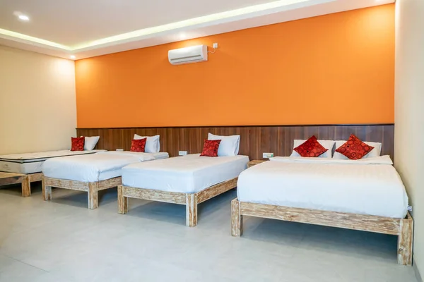 Photograph of bright white bedrooms with wooden bed, white mattress and red pillows