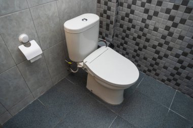 Seramik duvarlı, tuvalette kapalı beyaz bir tuvaletin fotoğrafı.