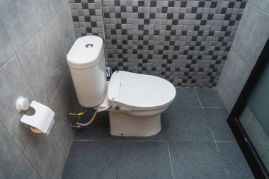 Seramik duvarlı, tuvalette kapalı beyaz bir tuvaletin fotoğrafı.