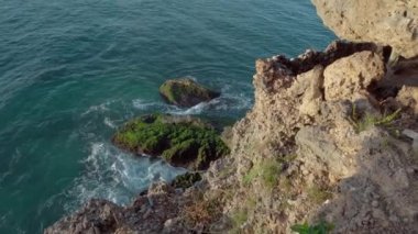 Mavi berrak su ve büyük keskin kayalarla deniz manzarasının videosu.