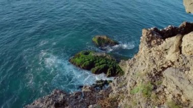 Mavi berrak su ve büyük keskin kayalarla deniz manzarasının videosu.