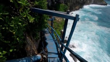 Eski ahşap merdivenlerde deniz ve kaya manzaralı yüksek bir dağdaki uçuruma uygun birinin videosu.