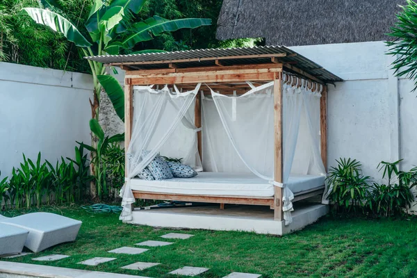 Dışarıdaki sivrisinek ızgarasının altında ahşap yataklı bir çardağın parlak fotoğrafı.