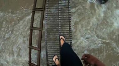 Eski metal merdivenlerde kayalık manzaralı yüksek bir dağdaki uçuruma uygun birinin videosu.