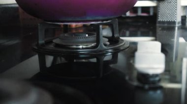 Mutfakta mavi ve kırmızı alevli siyah bir gaz sobasının 4K videosu.