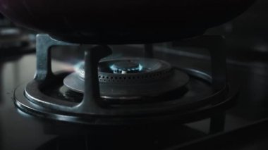 Mutfakta mavi ve kırmızı alevli siyah bir gaz sobasının 4K videosu.