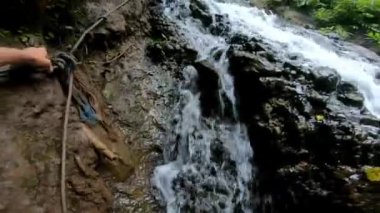 Ormanın yüksek bir dağdaki uçuruma kadar uzanan kayalık bir nehir ve yeşil ağaçla ilgili birinci şahıs videosu.