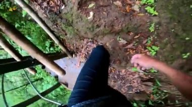 Yüksek bir dağdaki uçuruma kadar uzanan bir ormanın birinci şahıs videosu. Kayalar, yeşil ağaçlar ve yer cüceleri.