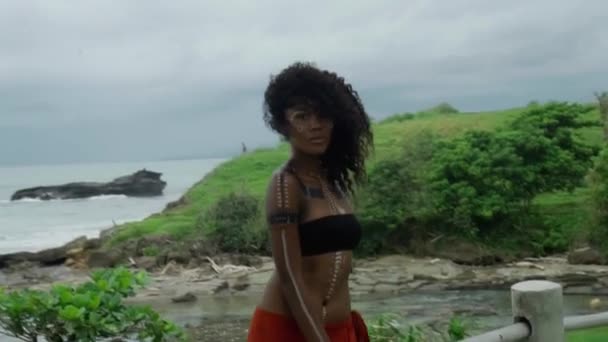 一个年轻美丽的黑发非洲女孩在热带花园行走的视频 她的脸上有化妆和族裔色彩 — 图库视频影像