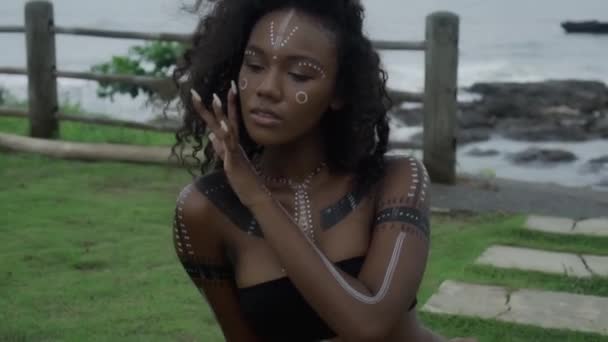 一个年轻美丽的黑发非洲女孩在热带花园行走的视频 她的脸上有化妆和族裔色彩 — 图库视频影像