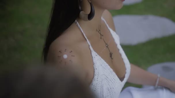 一个年轻美丽的黑发欧洲女孩坐在热带花园 化妆并在尸体上画上民族线条的视频 — 图库视频影像