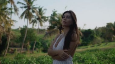 Güzel, genç, esmer Avrupalı bir kızın videosu. Makyajlı ve vücuduna etnik çizgiler çizmiş. Tropikal bir bahçede yürüyor.