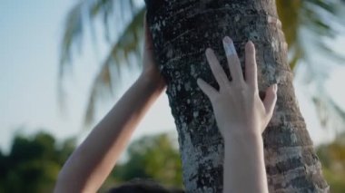 Güzel, genç, esmer Avrupalı bir kızın videosu. Makyajlı ve vücuduna etnik çizgiler çizmiş. Tropikal bir bahçede yürüyor.