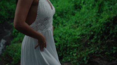 Güzel, genç, esmer Avrupalı bir kızın videosu. Makyajlı ve vücuduna etnik çizgiler çizmiş. Tropikal bir bahçede yürüyor.