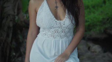 Güzel, genç, esmer Avrupalı bir kızın videosu. Makyajlı ve vücuduna etnik çizgiler çizmiş. Tropikal bir bahçede yürüyor.