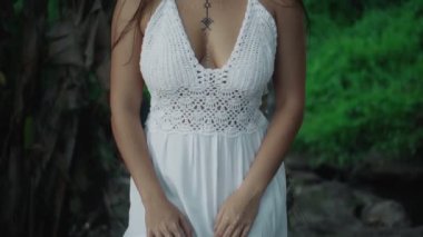 Güzel, genç, esmer Avrupalı bir kızın videosu. Makyajlı ve vücuduna etnik çizgiler çizmiş. Tropikal bir bahçede yürüyor.
