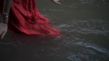Suda duran bir kızın videosu. Yağmur ormanlarında kırmızı elbiseli bir kızın nehirde yürüdüğü su.