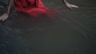 Suda duran bir kızın videosu. Yağmur ormanlarında kırmızı elbiseli bir kızın nehirde yürüdüğü su.