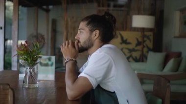 Genç yakışıklı Avrupalı esmer, uzun saçlı, boş bir kafede tek başına oturuyor. Kafasını çeviriyor ve tanıdık biriyle tanışmış gibi bakıyor.