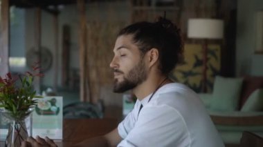 Genç yakışıklı Avrupalı esmer, uzun saçlı, boş bir kafede tek başına oturuyor. Kafasını çeviriyor ve tanıdık biriyle tanışmış gibi bakıyor.