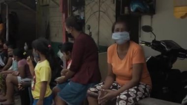 Benoa, Kuta, Kabupaten Badung, Bali, Endonezya - 8 Temmuz 2020: Yüzlerinde maskeli insanlar ve çocukların olduğu Endonezya 'daki küçük bir köyün videosu