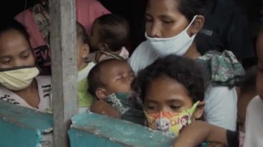 Benoa, Kuta, Kabupaten Badung, Bali, Endonezya - 8 Temmuz 2020: Yüzlerinde maskeli insanlar ve çocukların olduğu Endonezya 'daki küçük bir köyün videosu