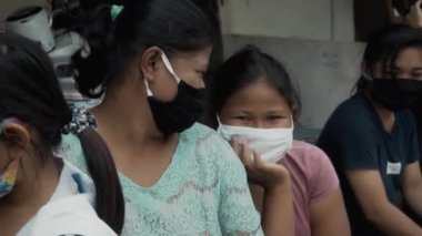 Benoa, Kuta, Kabupaten Badung, Bali, Endonezya - 8 Temmuz 2020: Yüzlerinde maskeli insanlar ve çocukların olduğu Endonezya 'daki küçük bir köyün videosu
