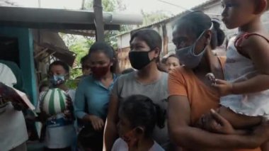 Benoa, Kuta, Kabupaten Badung, Bali, Endonezya - 8 Temmuz 2020: Yüzlerinde maskeli insanlar ve çocukların olduğu Endonezya 'daki küçük bir köyün videosu