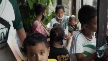 Benoa, Kuta, Kabupaten Badung, Bali, Endonezya - 8 Temmuz 2020: Yüzlerinde maskeli insanlar ve çocukların olduğu Endonezya 'daki küçük bir köyün videosu